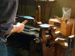 Ein glühendes Metallstück wird mit dem Hammer bearbeitet.