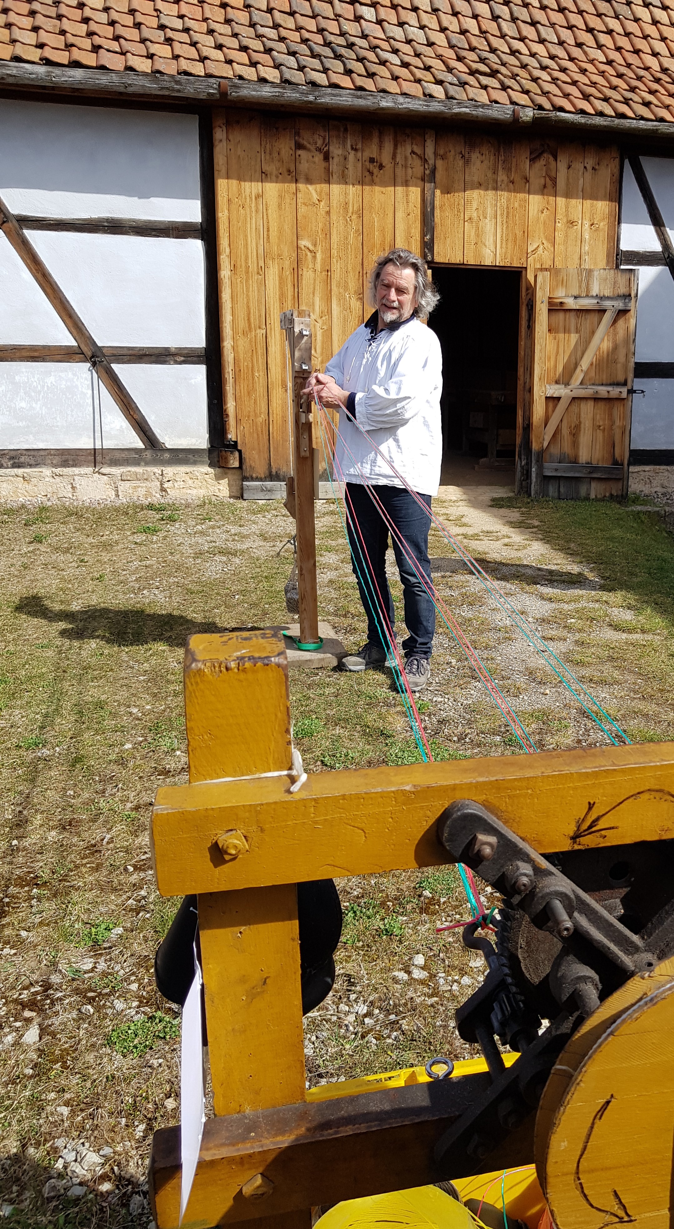 Ein Seilhersteller mit vielen gespannten Stricken auf der Wiese.