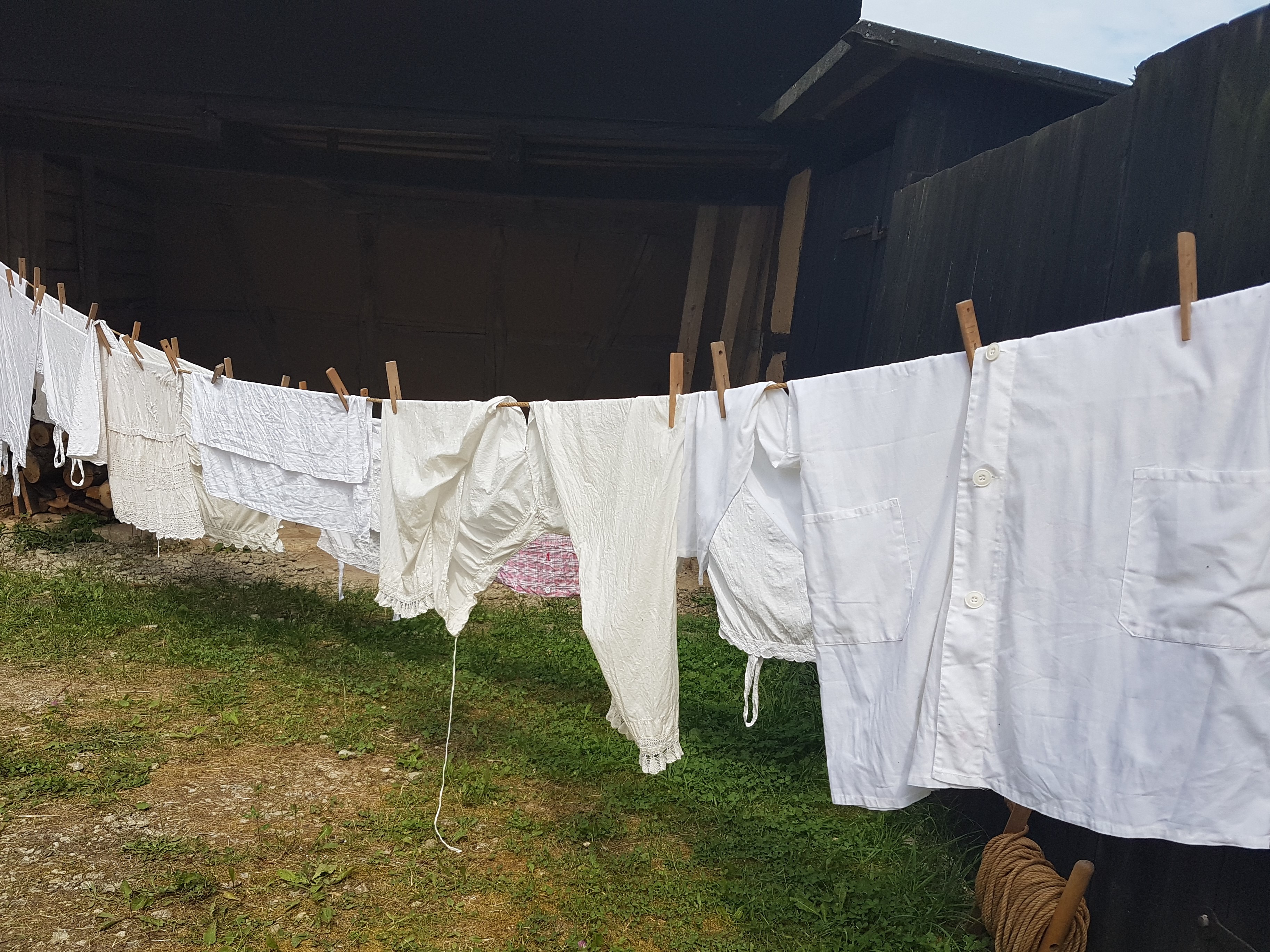 Auf einer langen Leine wurden weiße Unterröcke und Hemden mit Rüschen mit Holz-Wäscheklammern aufgehängt. 