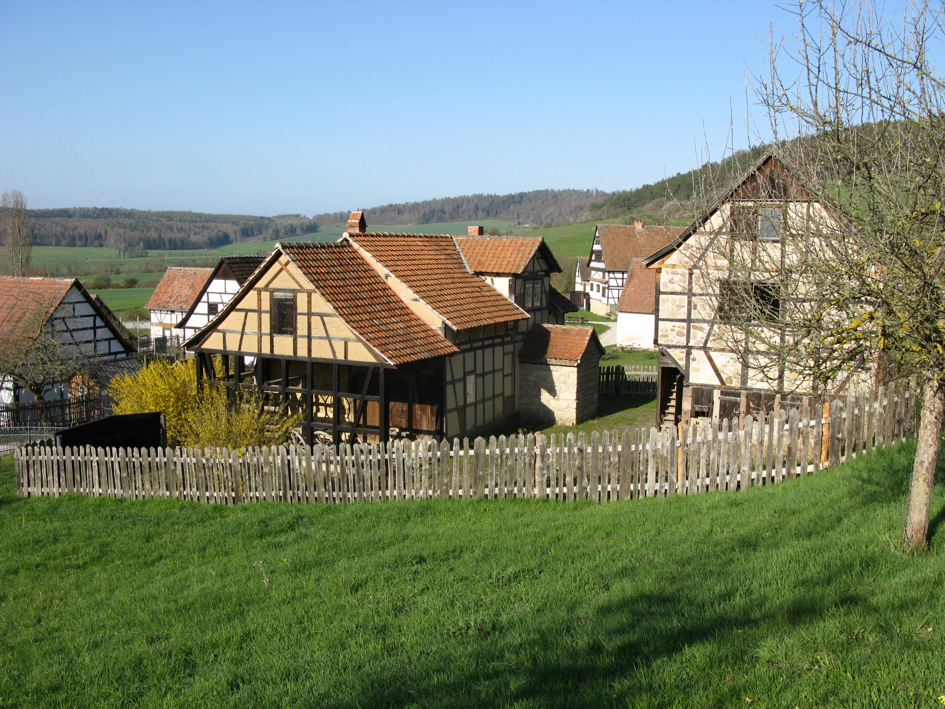 Ein Museumsdorf auf dem grünen Gelände ist hübsch eingezäunt.